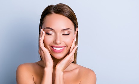 Portrait of pleased satisfied girl touching face enjoying ideal perfect skin after procedure mask keeping eyes closed isolated on grey background